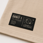 Close-up of the woven waistline tag on the GLXY Orbit 001 Vintage Cream t-shirt