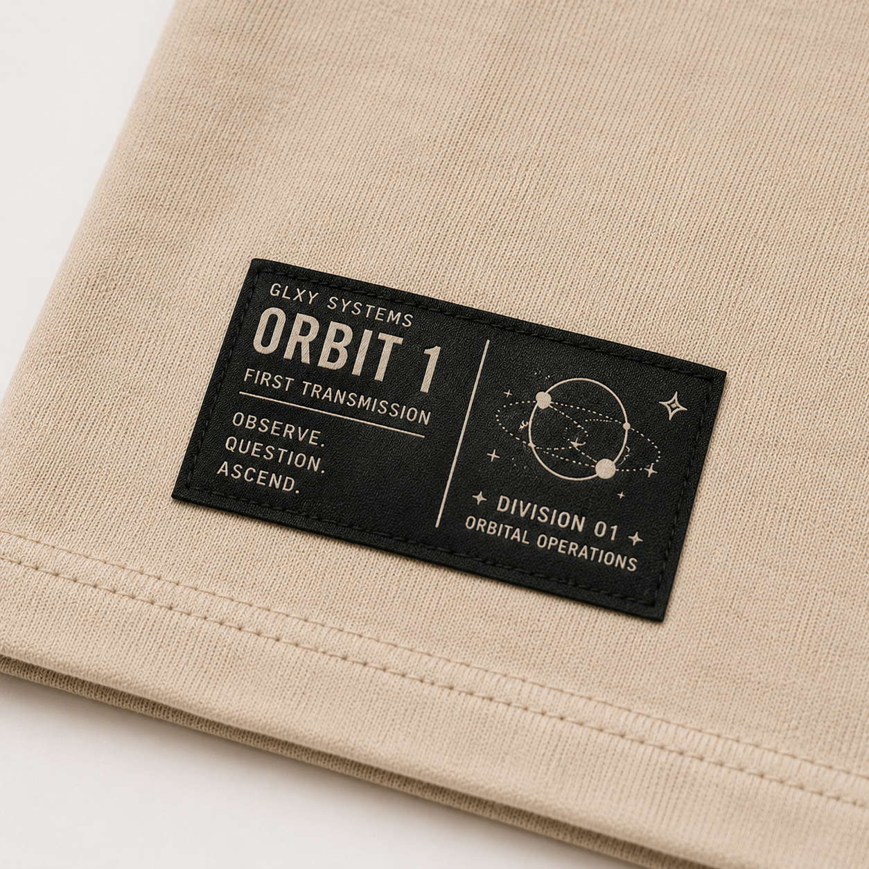 Close-up of the woven waistline tag on the GLXY Orbit 001 Vintage Cream t-shirt