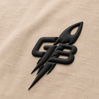 Close-up of the tonal black puff-print GB rocket emblem on the GLXY Orbit 001 Vintage Cream t-shirt