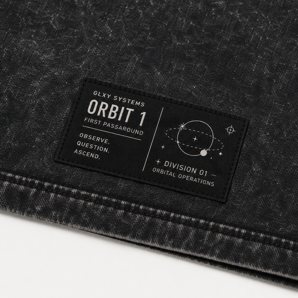 Close-up of the woven waistline tag on the GLXY Orbit 001 Vintage Black t-shirt